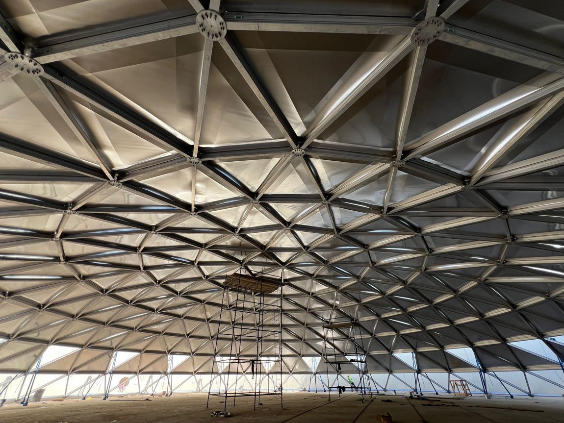 Underside view of an aluminum geodesic dome space frame showing struts and gusset hubs