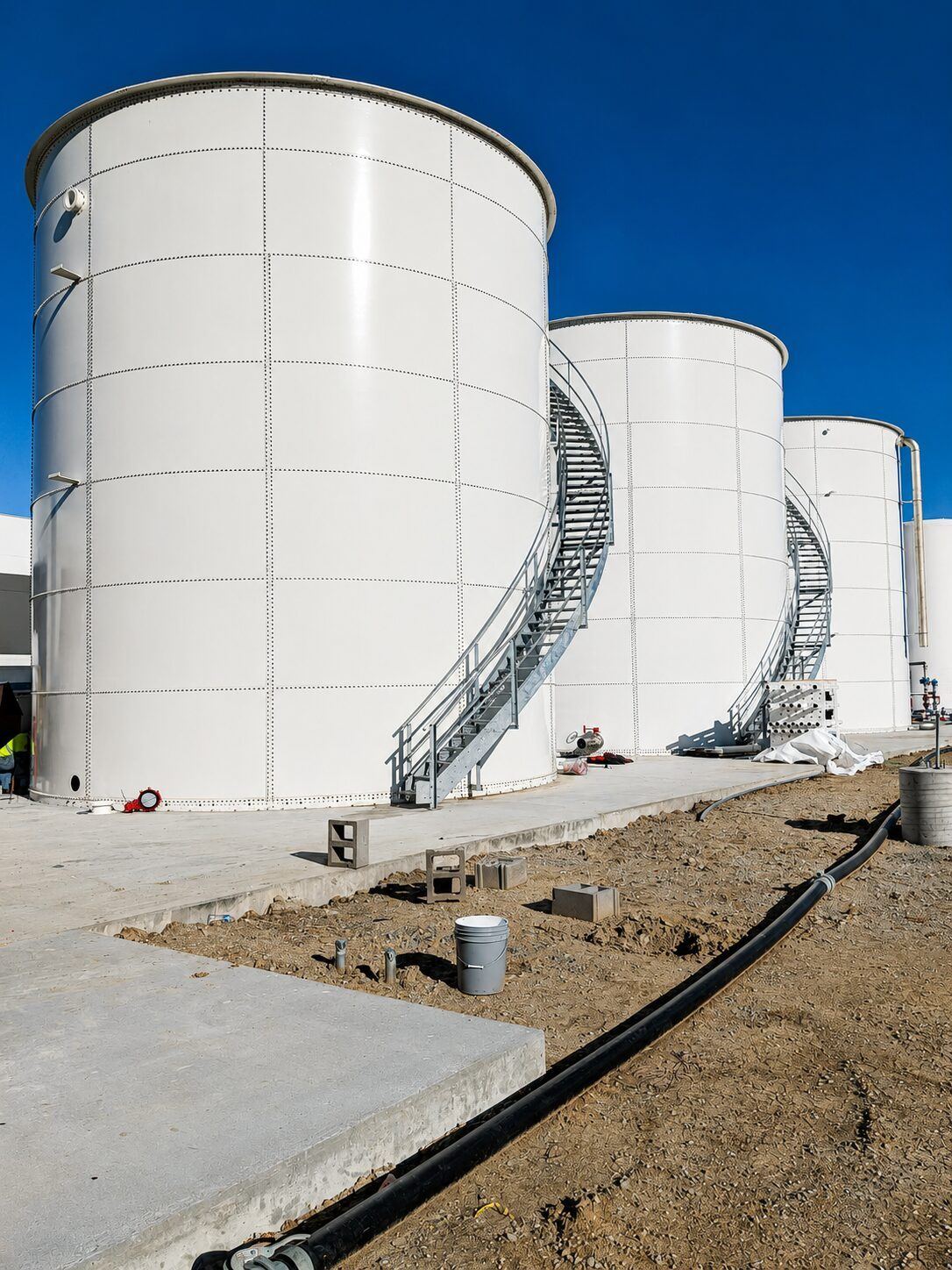 Bolted steel tank being installed with a crane on an active jobsite