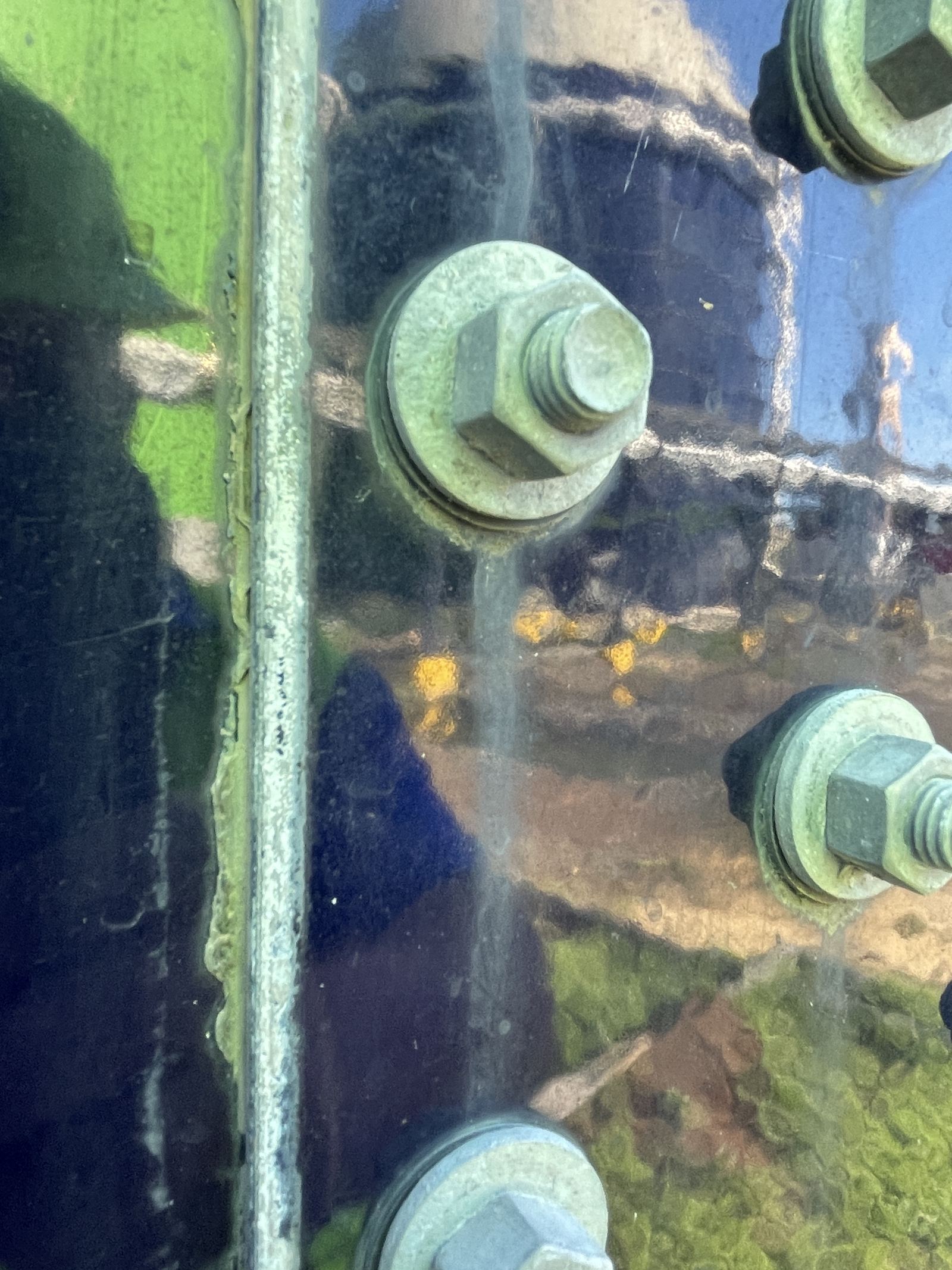Close-up of bolt heads and washers along a bolted tank panel seam