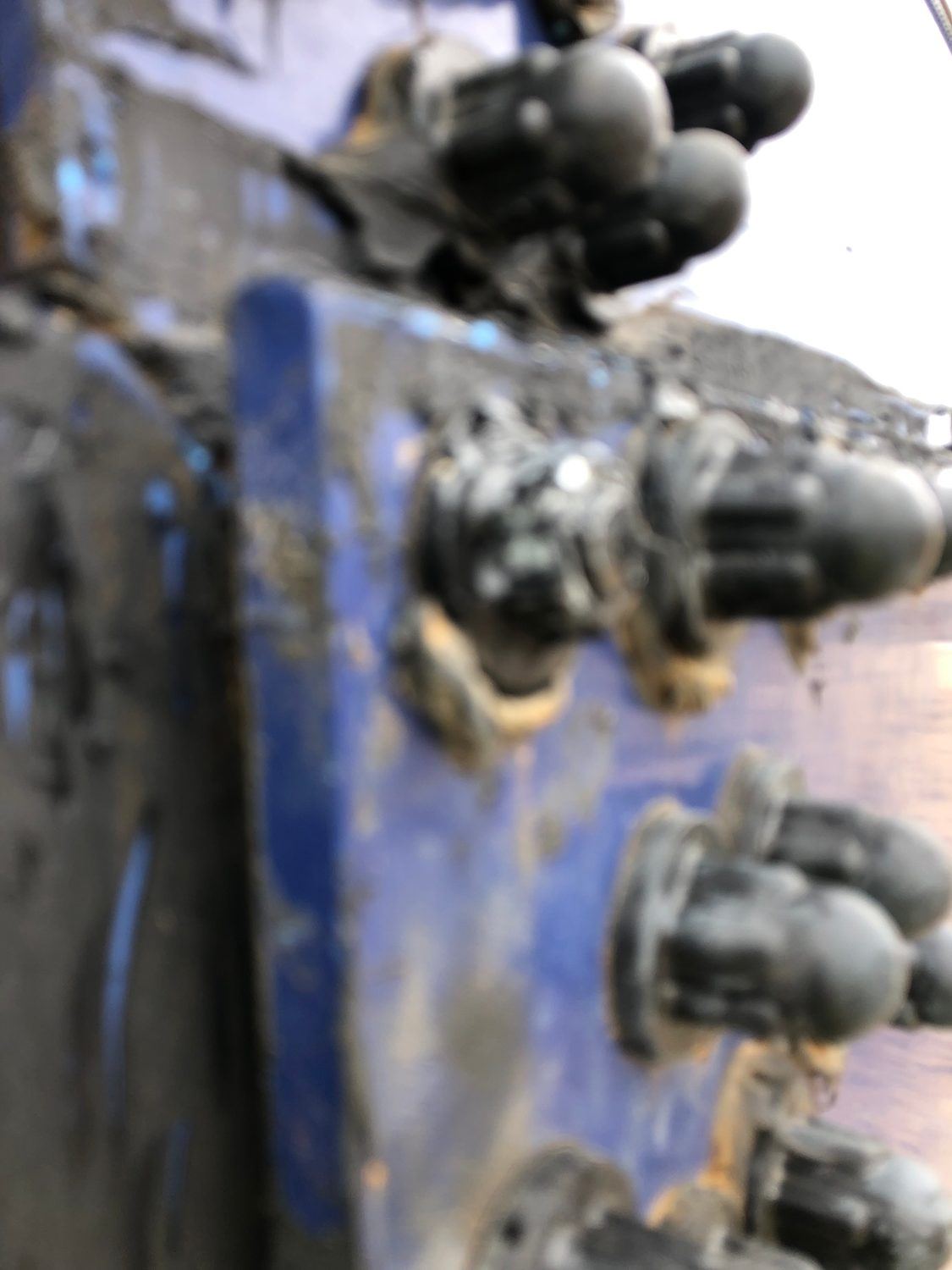 Corroded bolt heads and fasteners on a bolted tank panel