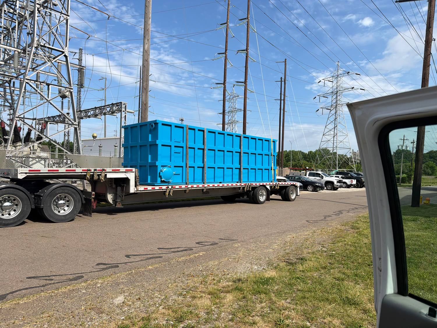 Blue modular bolted steel tank loaded on a flatbed trailer, coated and ready to ship from the plant