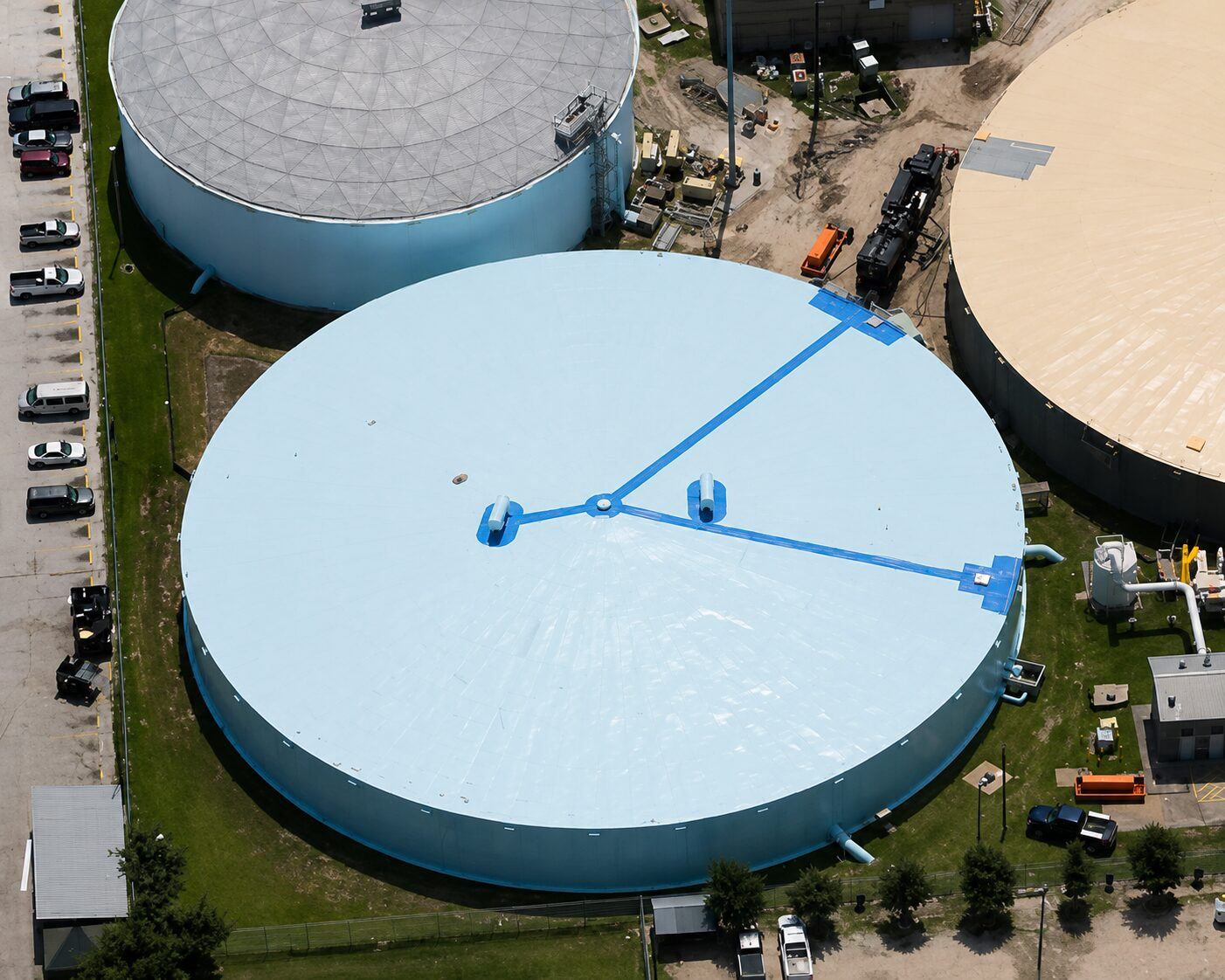 Aerial view of a freshly coated light blue circular tank roof with coating equipment visible