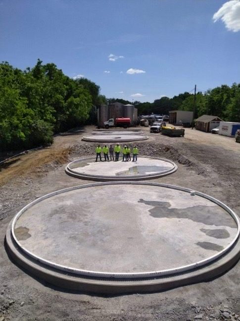 Aerial of three completed concrete ring-wall tank foundations with the crew standing in one