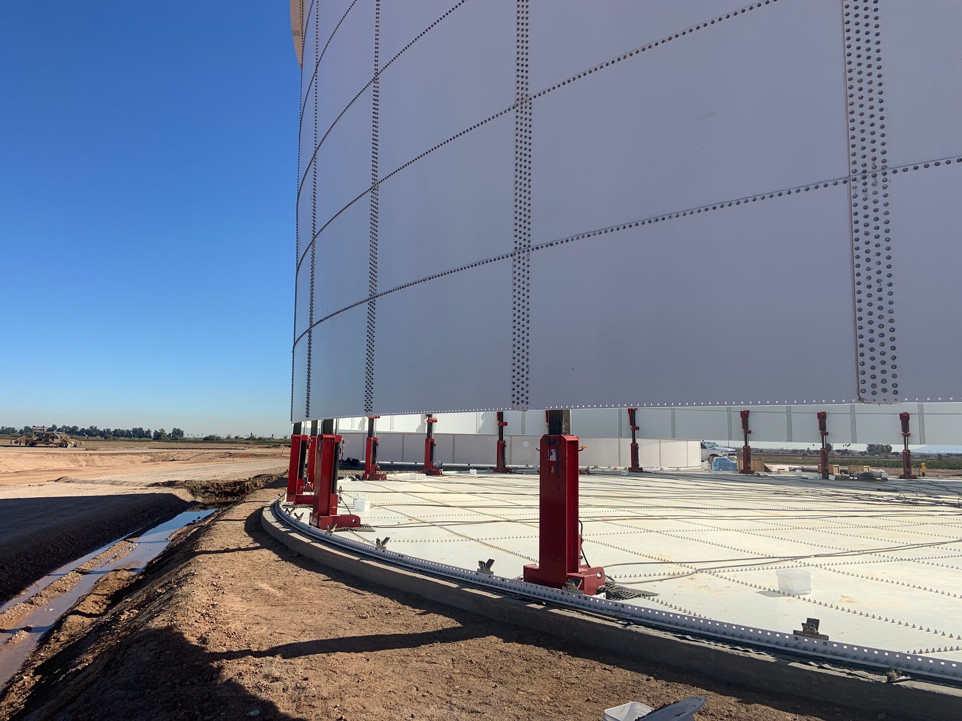 Two completed bolted steel storage tanks on concrete pad at industrial facility