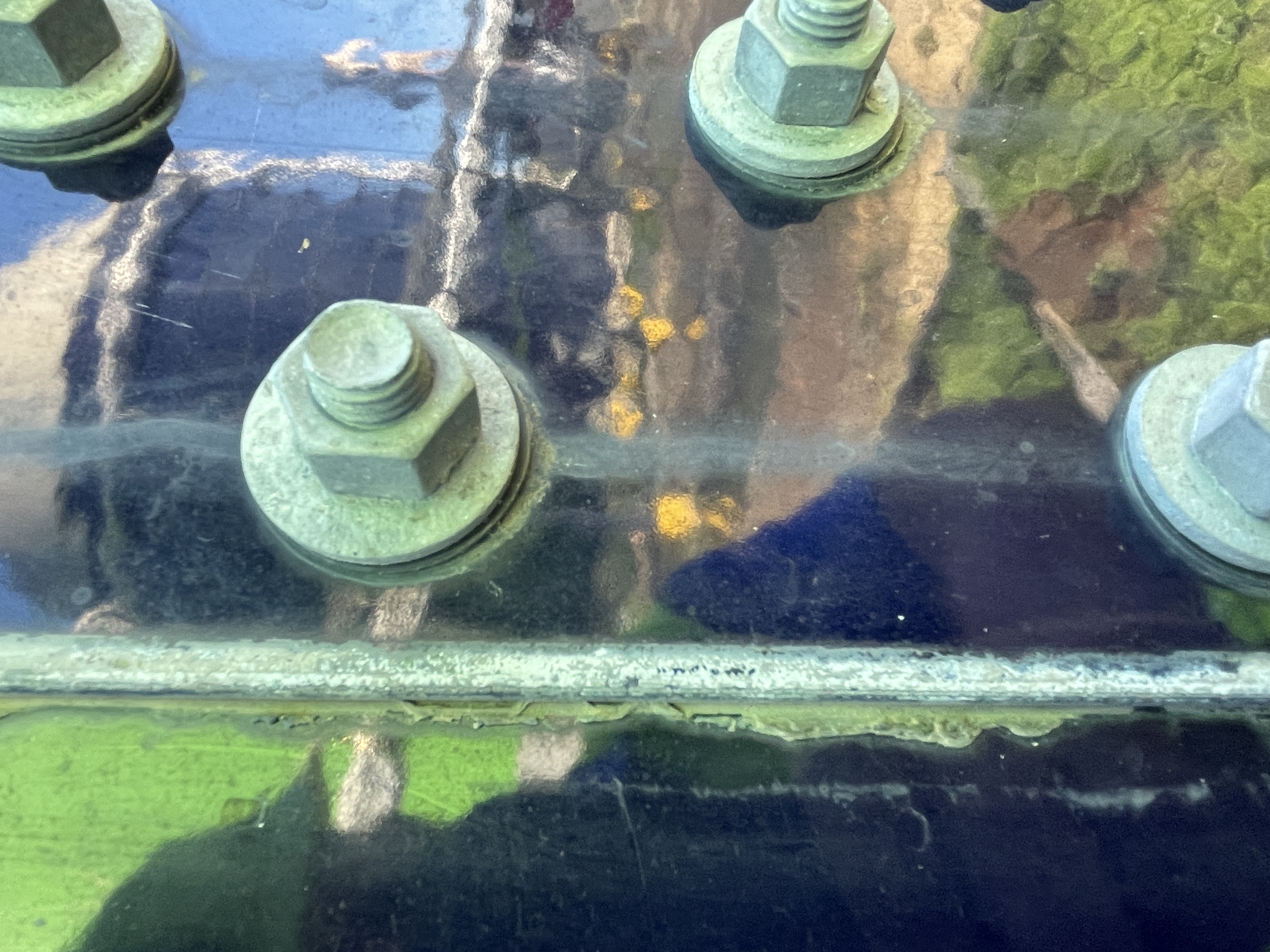 Close-up of bolt heads and washers along a bolted tank panel seam