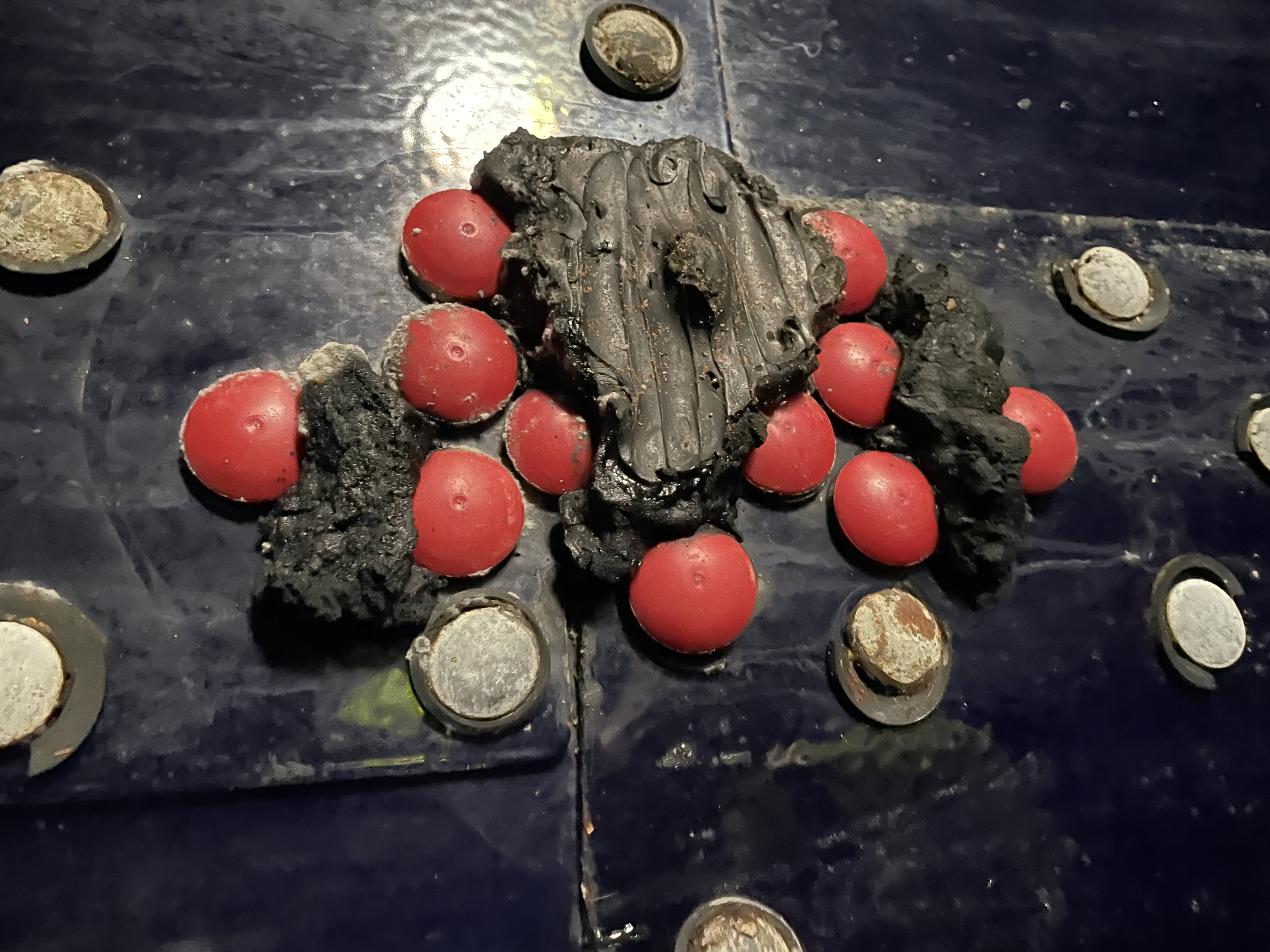 Black mastic sealant applied over bolt caps on a blue tank panel